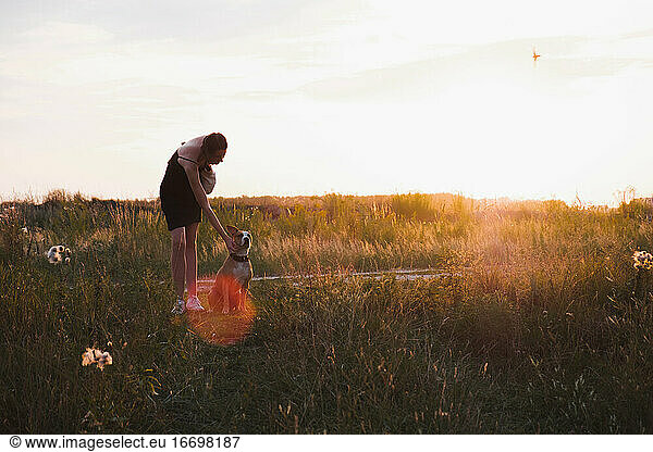 Young woman stands in the field with dog  faded colors during su