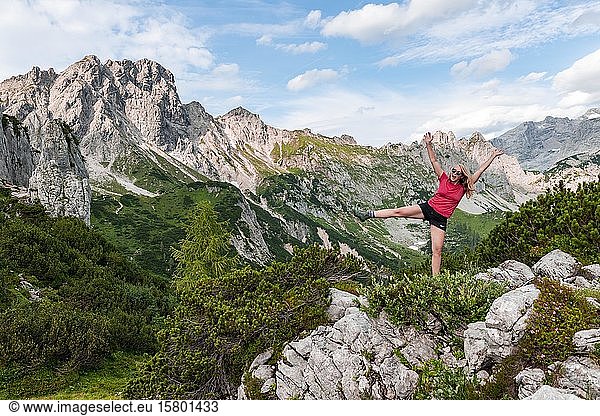 Young woman stretches arms in the air  Rugged mountain tops  mountains  Armkarwand  Große Bischofsmütze  Salzkammergut  Upper Austria  Austria  Europe