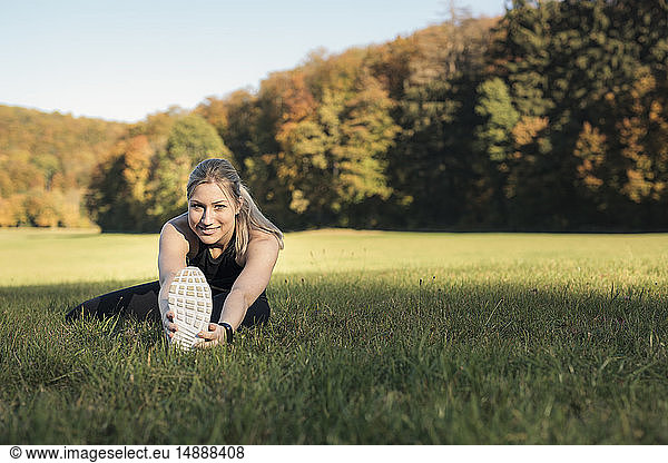 Young woman stretching her leg on a meadow