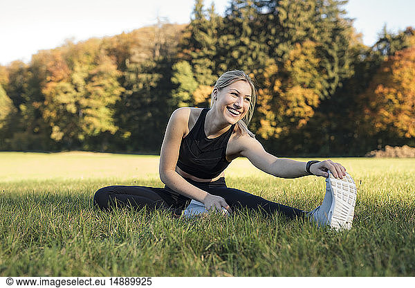 Young woman stretching her leg on a meadow