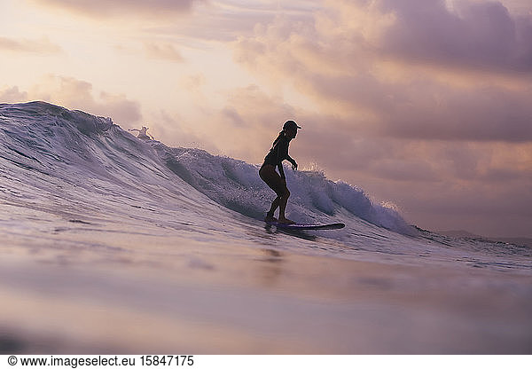 Young woman surfing at sunset