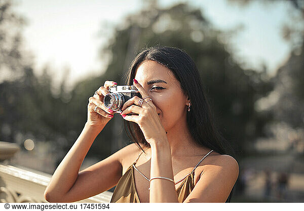 young woman takes a photograph with a vintage camera