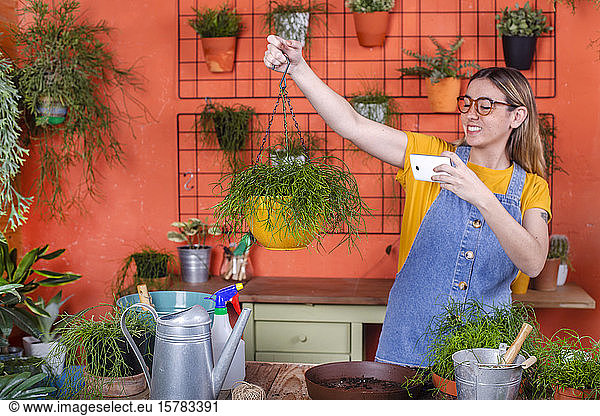 Young woman taking cell phone picture of her Rhipsalis plant