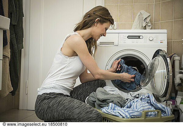 Young woman taking laundry out of washing machine  Munich  Bavaria  Germany