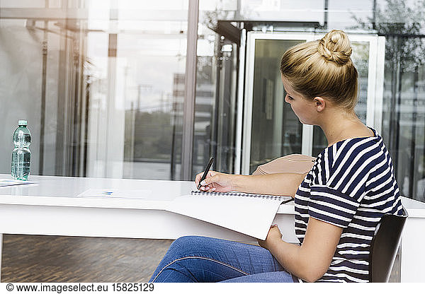 Young woman taking notes in office