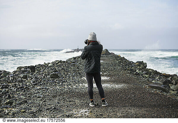 Young Woman taking photograph alone on Oregon jetty