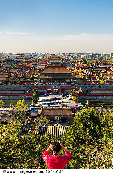 Young woman taking photograph of view over Forbidden City in Beijing  China