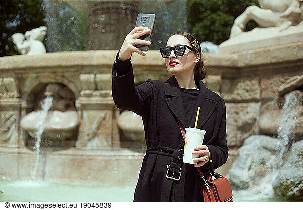 Young woman taking selfie by the fountain