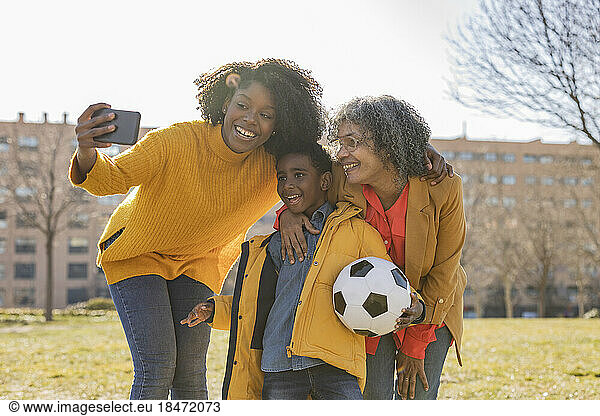 Young woman talking selfie with family in park on sunny day