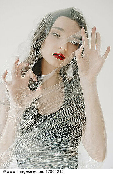 Young woman tearing hole in plastic