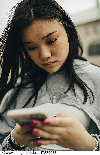 Young woman text messaging through smart phone