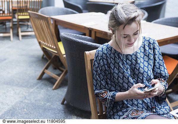 Young woman text messaging while sitting at restaurant
