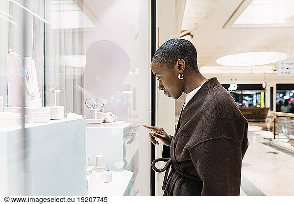 Young woman touching glass of store window