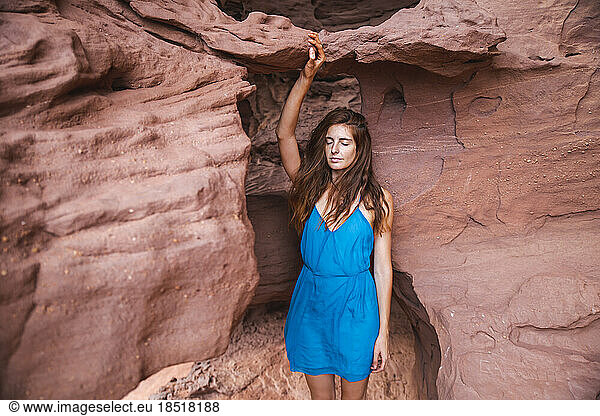Young woman touching rock in red cave