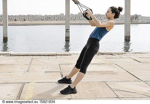 Young woman training on ropes at harbour