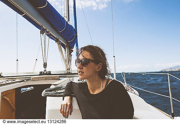 Young woman travelling in sailboat on sea against sky