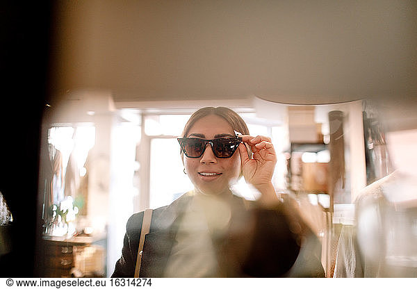 Young woman trying sunglasses at fashion store