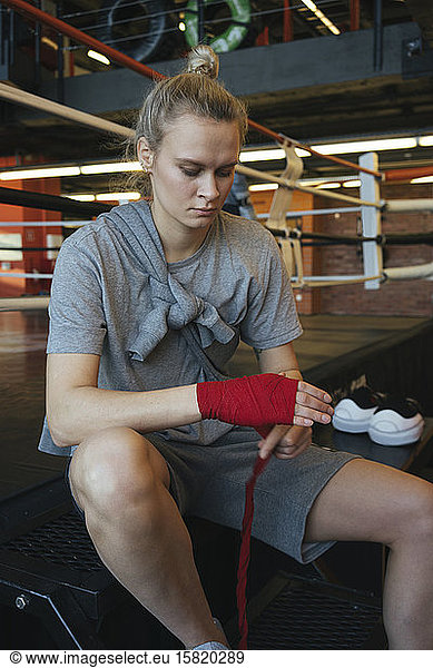 Young woman tying bandage around her hand in boxing club