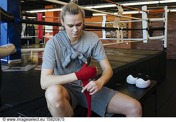 Young woman tying bandage around her hand in boxing club