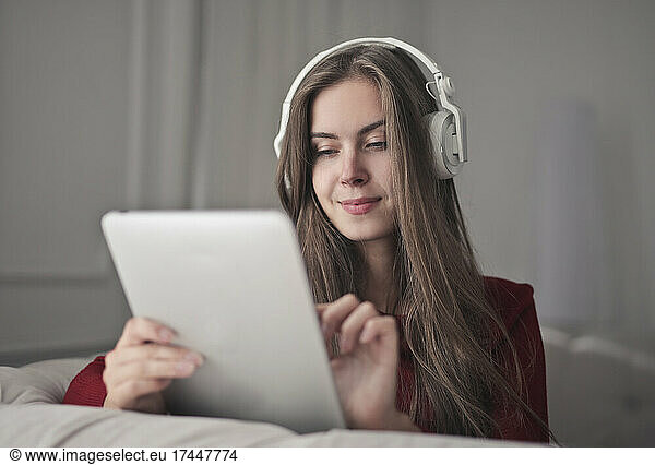 young woman uses a tablet and listens to music