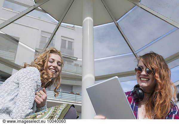 Young woman using a digital tablet with her friend  Munich  Bavaria  Germany