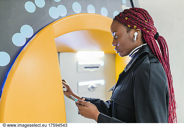 Young woman using ATM machine