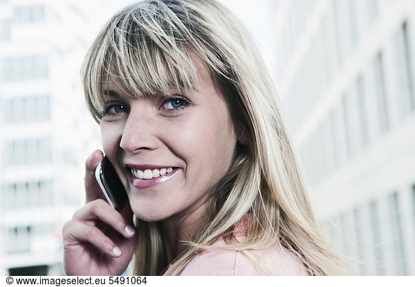 Young woman using cell phone  smiling  portrait