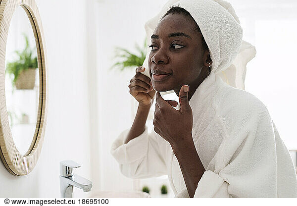 Young woman using Guasha scraper massager in bathroom at home