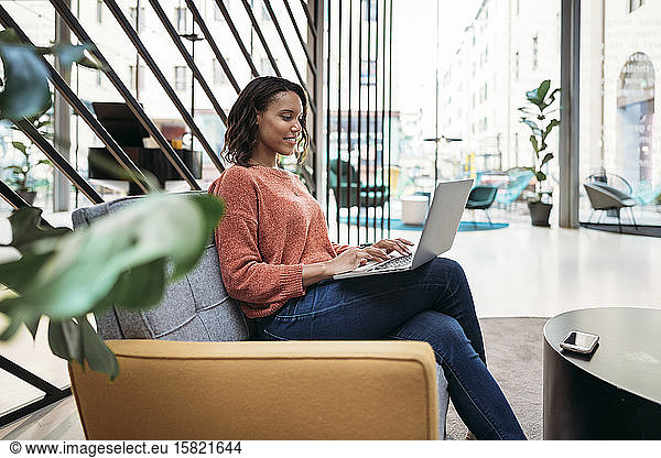 Young woman using laptop in a foyer