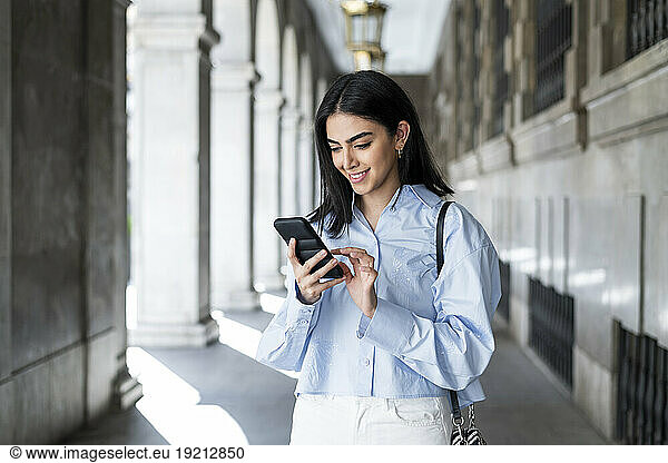 Young woman using smart phone in colonnade