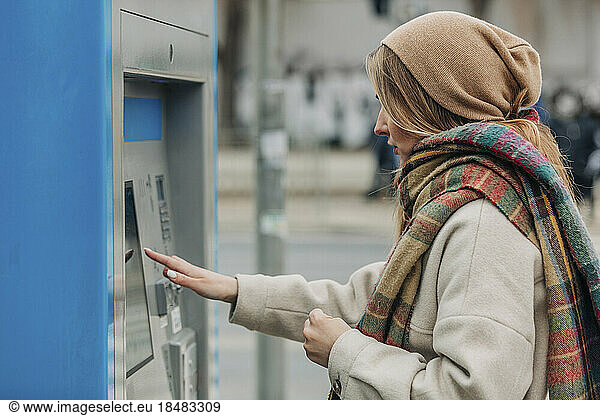 Young woman using ticket vending machine