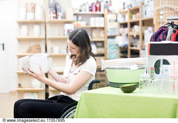 Young woman using wheelchair browsing in shop