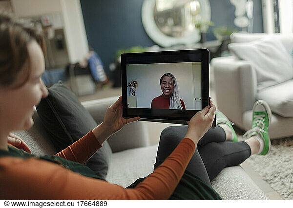 Young woman video chatting with friend on digital tablet screen