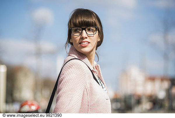Young woman walking in street using mobile phone