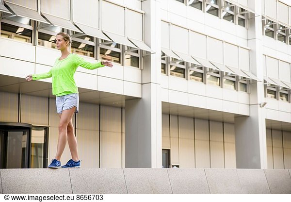 Young woman walking on wall