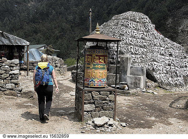 Young woman walking past prayer wheel  Manjo  Solo Khumbu  Nepal