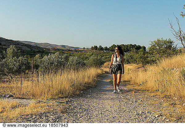 Young woman walks through a dirt road in a meadow