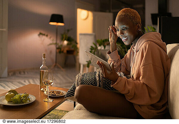 Young woman watching movie on tablet while relaxing at home