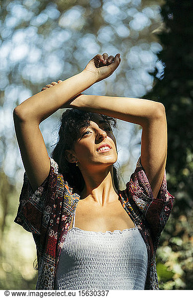Young woman wearing a colorful shirt and white top looking to the sun with crossed arms on her forehead