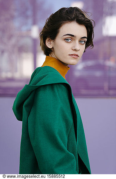 Young woman wearing green coat in front of a glass pane