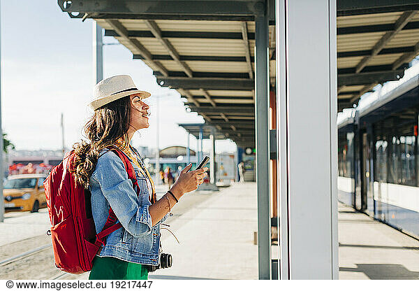 Young woman wearing hat going through route map at tram station