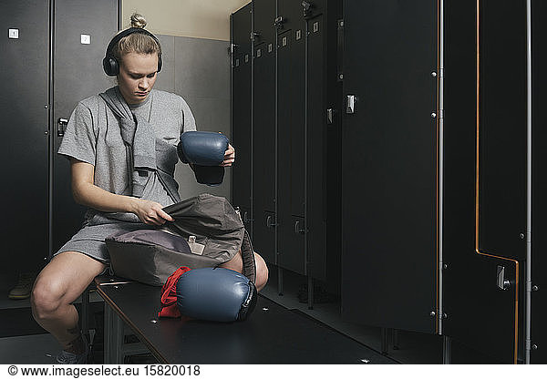 Young woman wearing headphones in locker room of a boxing club