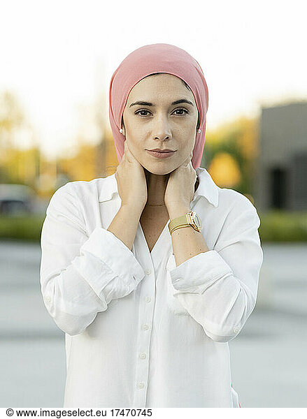 Young woman wearing headscarf with hands behind head
