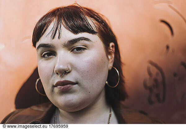 Young woman wearing nose ring against wall