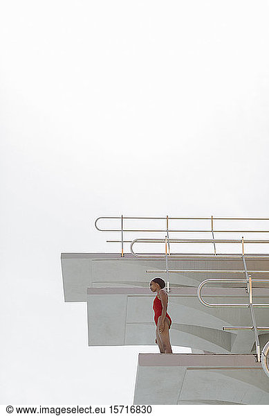 Young woman wearing red bathsuit standing on highboard