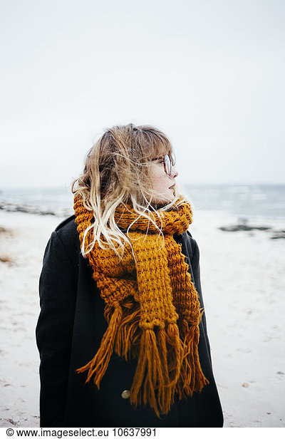 Young woman wearing scarf while looking away at beach