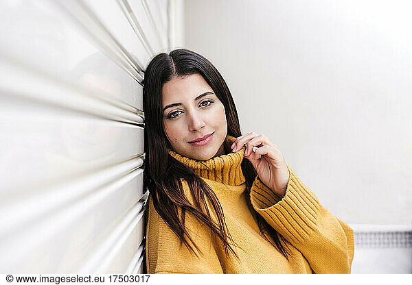 Young woman wearing sweater leaning on wall