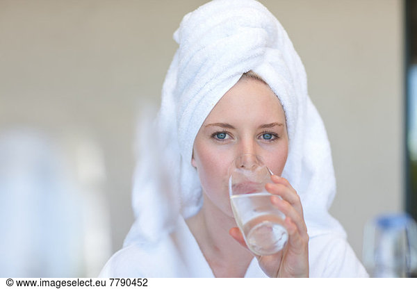 Young woman wearing towel on head drinking water