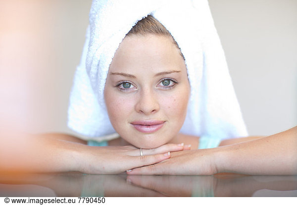 Young woman wearing towel on head with chin on hands