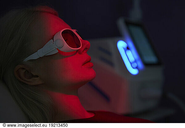 Young woman wearing virtual reality headset amidst red neon light